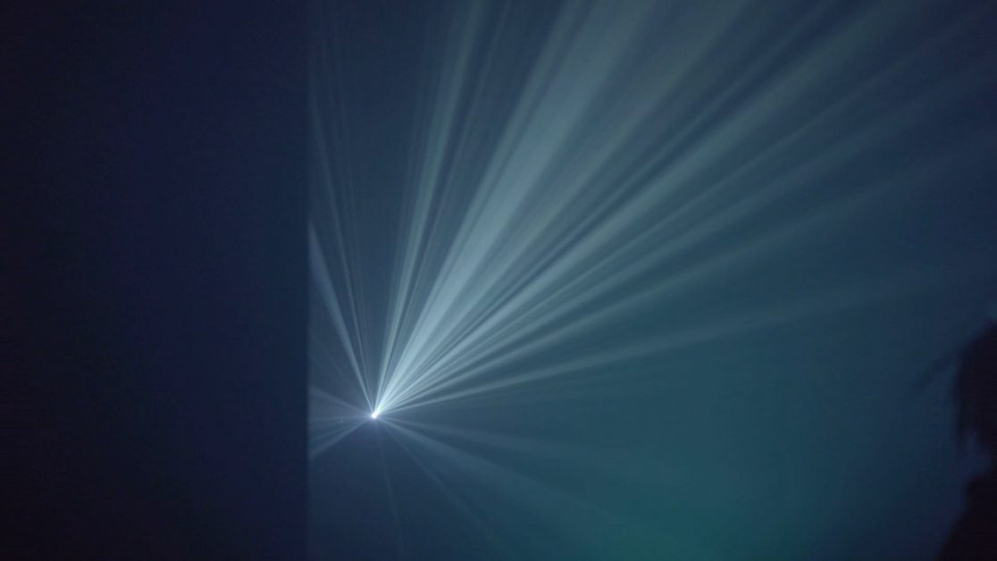 Projection of twinkly blue light beams in Strange Loop performance