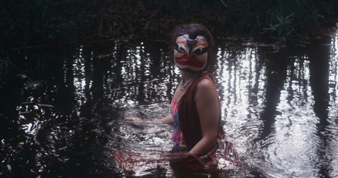 women in ritual mask in water