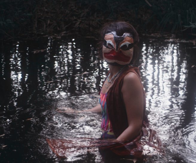 women in ritual mask in water
