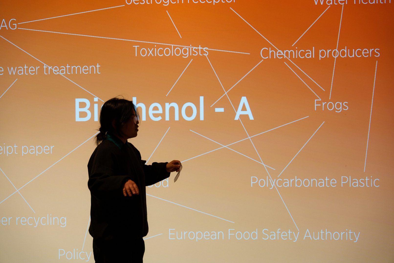 Woman standing in front of orange image with text