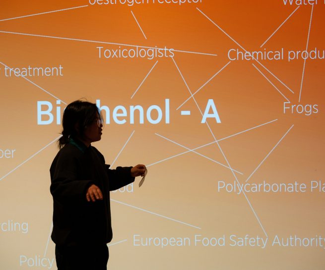 Woman standing in front of orange image with text