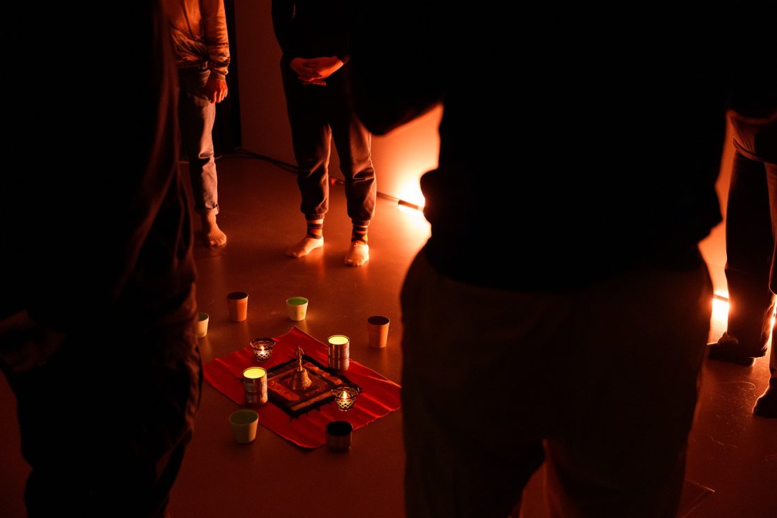 a group in silhouette in dark space lit by candles